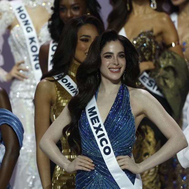 Eine strahlende Teilnehmerin mit der Schärpe "MEXICO" posiert in einem glitzernden, blauen Kleid.