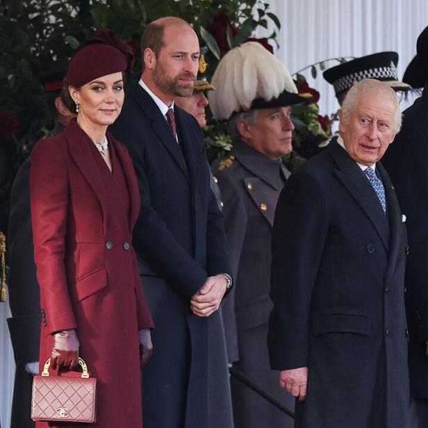 König Charles, Prinz William und Prinzessin Kate in Mänteln bei einer Veranstaltung.
