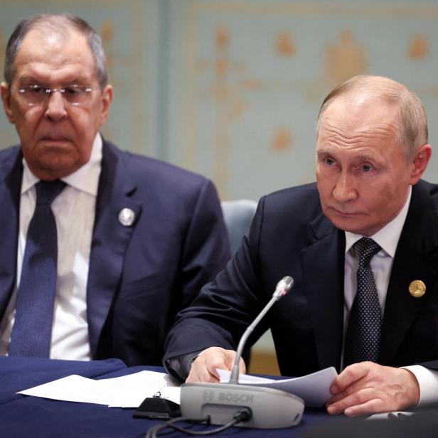 Putin sitzt mit Lawrow am Tisch und liest Papiere.