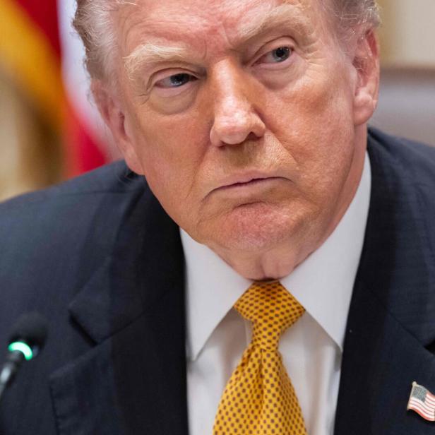 Donald Trump blickt mit ernstem Gesichtsausdruck und gelber Krawatte in die Ferne.