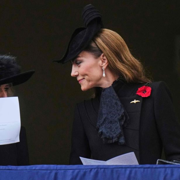 Camilla und Kate, beide mit Hüten und dunkler Kleidung, stehen auf einem Balkon.