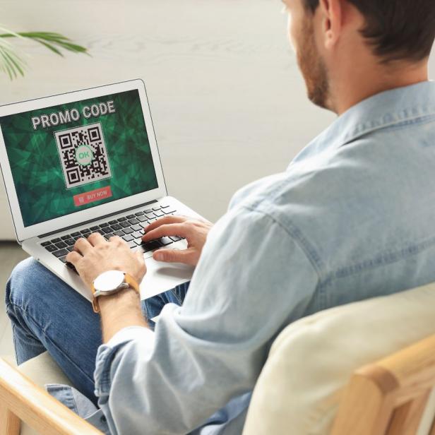 Mann arbeitet an Laptop, auf dessen Bildschirm ein QR-Code angezeigt wird.