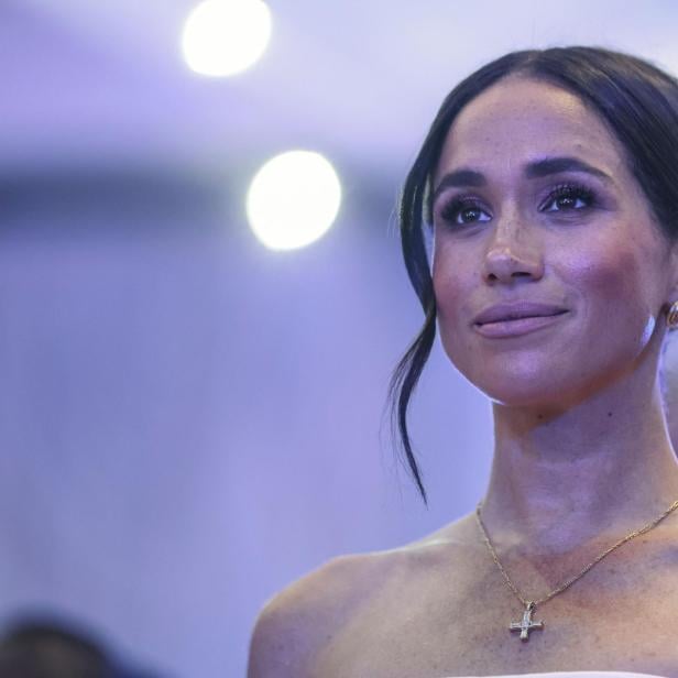Herzogin Meghan, mit hochgestecktem Haar und Halskette, blickt aufmerksam zur Seite.