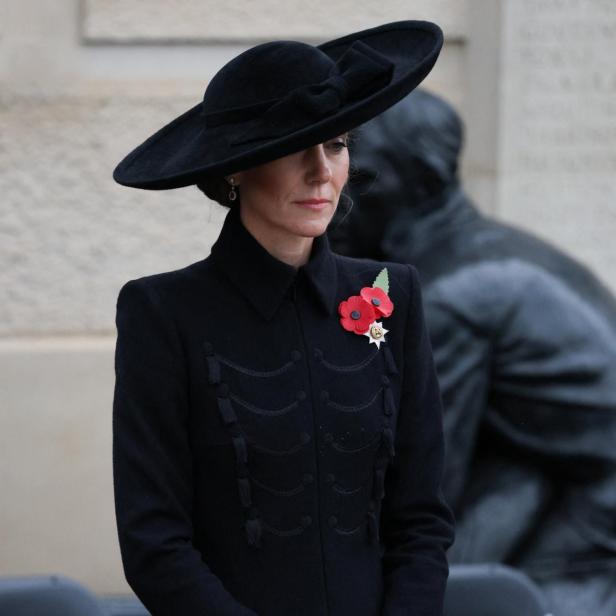 Prinzessin Kate, mit einem Schleierhut und einer Perlenkette, blickt gesenkt.