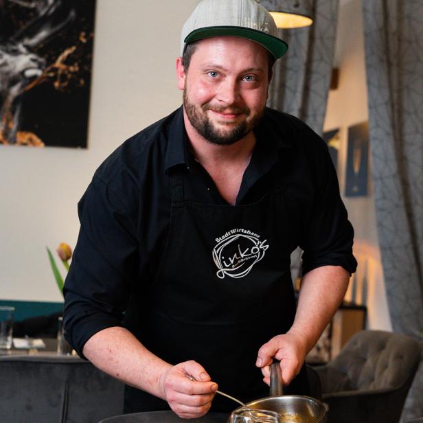 Ein Mann mit Cappie richtet Essen an. // Linko´s Bachstüberl überzeugt in Purkersdorf mit regionaler Küche, kreativen Menüs und nachhaltigem Gasthauskonzept.