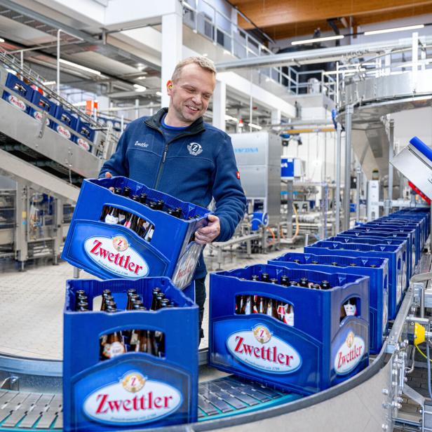 Arbeiter hebt Zwettler-Bierkiste von einem Förderband. DIe neue Abfüllanlage der Privatbrauerei Zwettl erstreckt sich über 3.000 Quadratmeter.