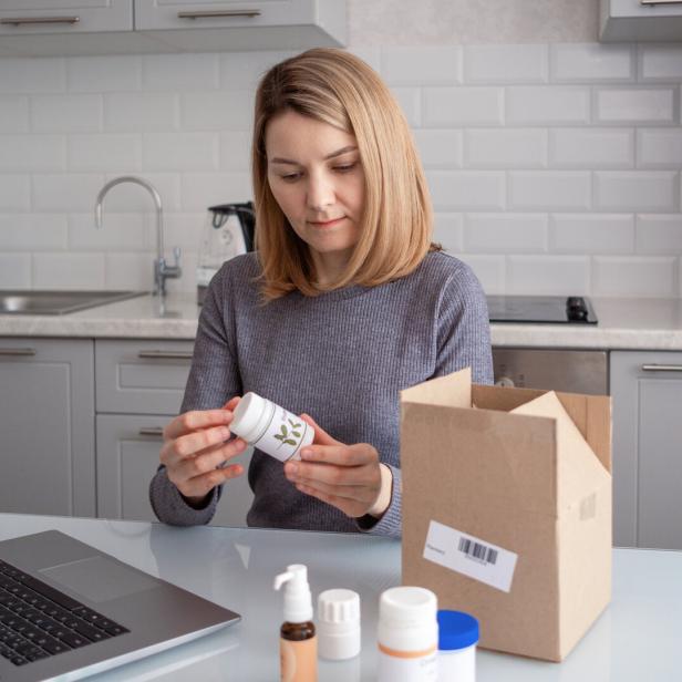 A woman opens a box with biologically active additives. Ordering food additives via the Internet.