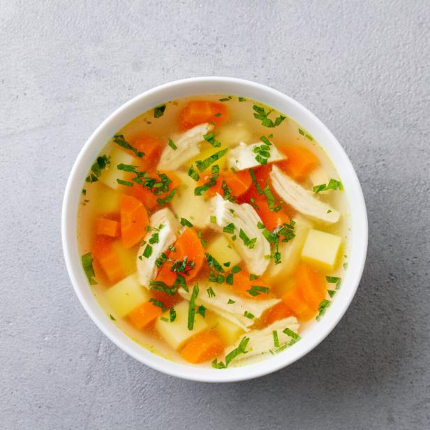 Eine Hühnersuppe mit Petersilie, Karotten und gelber Rübe.