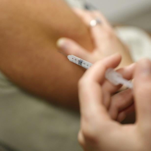 Eine Person erhält eine Injektion mit einer Spritze in den Oberarm.