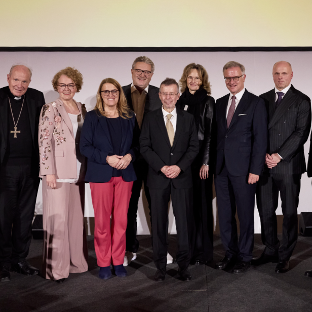 Eine Gruppe von Menschen steht in schicken Klamotten nebeneinander 