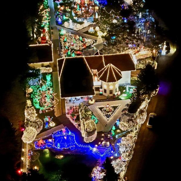 Ein Haus und Garten sind üppig mit bunten Weihnachtslichtern, Figuren und Dekorationen geschmückt.