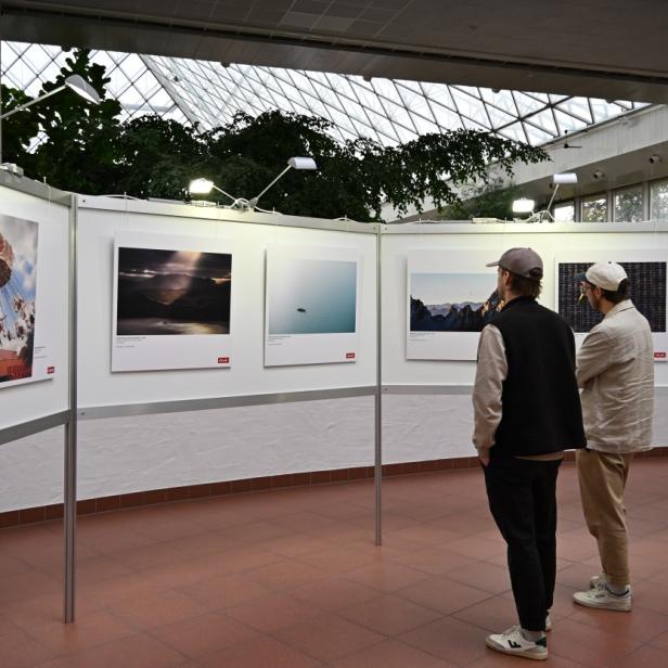 Zwei Männer begutachten Fotografien im Rahmen der Messe Photo + Adventure an.