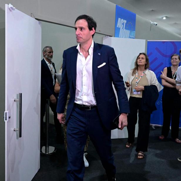 Wopke Hoekstra verlässt einen Raum, während andere Personen im Hintergrund stehen.