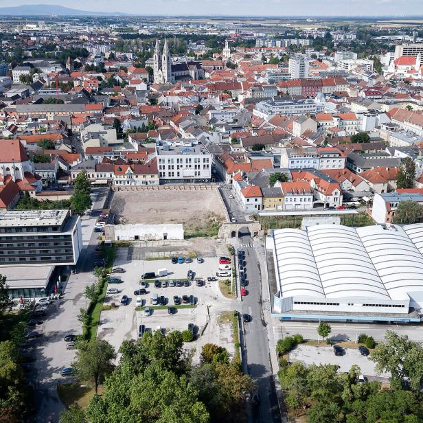 Die Aufnahme zeigt einen Blick auf Wiener Neustadt mit Gebäuden, Parkplätzen und Grünflächen.