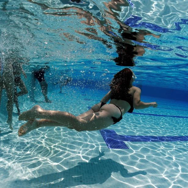 Ein Mädchen taucht unter dem Wasser - knapp über dem Grund.