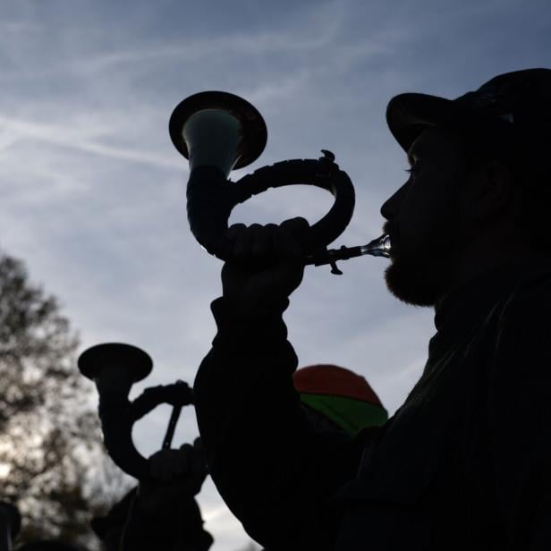 Das Foto zeigt einen Jäger in sein Jagdhorn blasen.