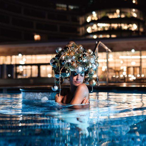 Eine Frau ist mit einer Lichterkette in einem Außenfreibad 