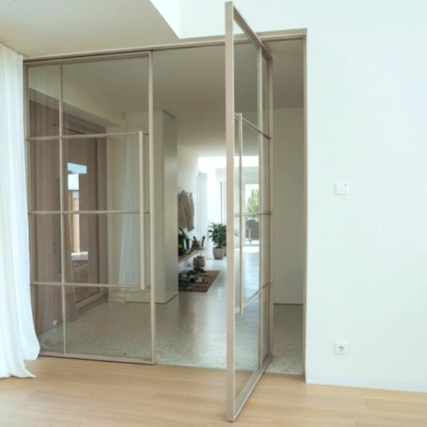 Ein heller Raum mit einer weißen Wand und einer großen Schiebetür aus Glas.