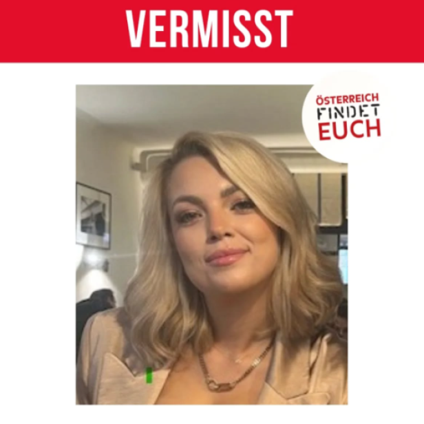 Junge Frau mit schulterlangem blondem Haar und beigem Blazer sitzt in einem Raum und lächelt leicht.