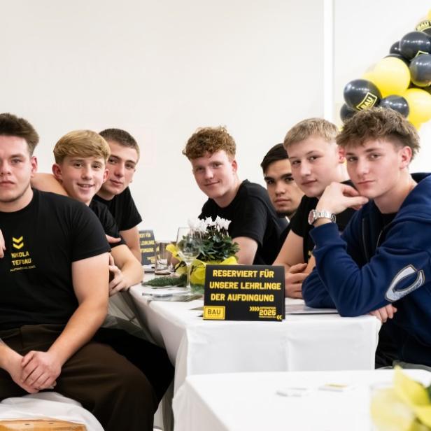 Mehrere Jugendliche sitzen an einem Tisch und schauen in die Kamera.