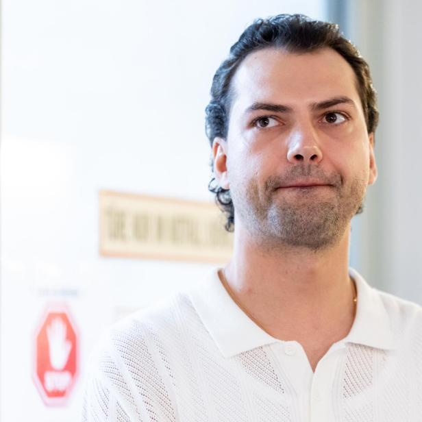 Jimi Blue Ochsenknecht mit dunklen Haaren und Bart trägt ein weißes Hemd und schaut zur Seite.