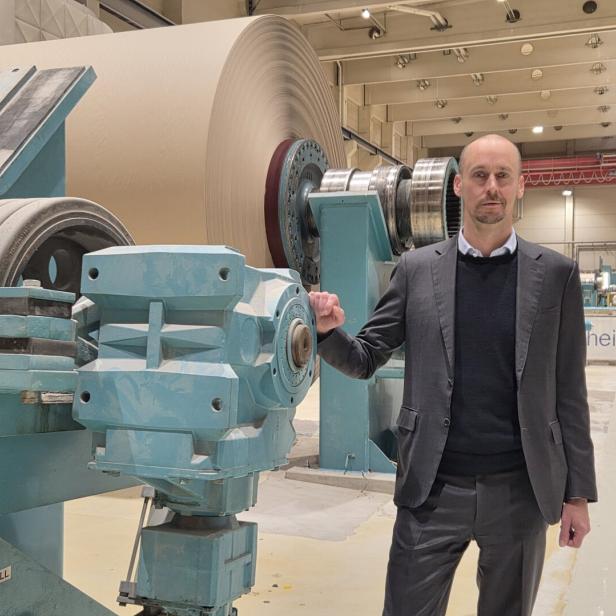 Mann im Anzug steht in einer Produktionshalle