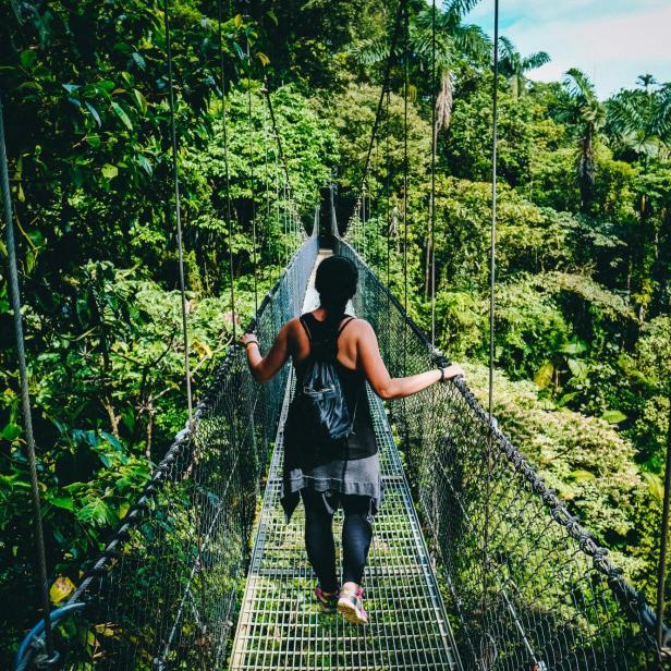 Eine Frau spaziert über eine Brücke im Dschungel Costa Ricas