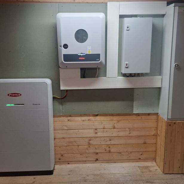 PV-Speicher, Wechselrichter und Schaltschrank an einer Holzwand in einem Technikraum.
