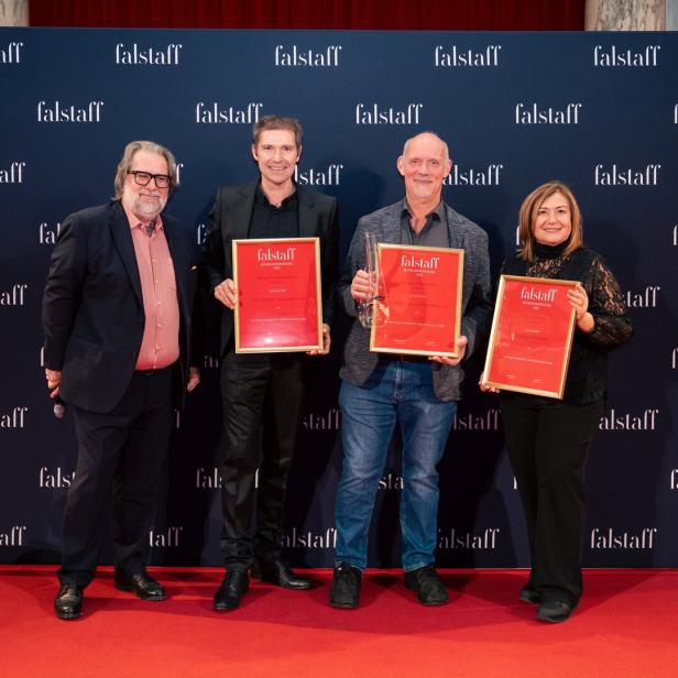 Vier Personen stehen auf rotem Teppich vor einer Wand mit „falstaff“-Schriftzug und halten gerahmte Auszeichnungen.