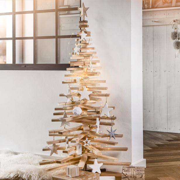 Holzweihnachtsbaum mit Lichterkette und weißen Sternen in modernem Wohnzimmer dekoriert.