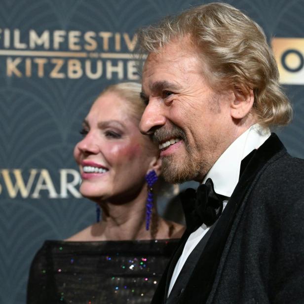 Thomas Gottschalk und eine Frau lächeln vor dem Hintergrund des Filmfestivals Kitzbühel.