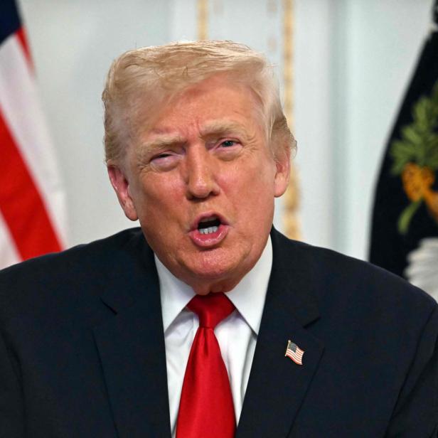 Donald Trump spricht vor US-Flagge und Staatssiegel.