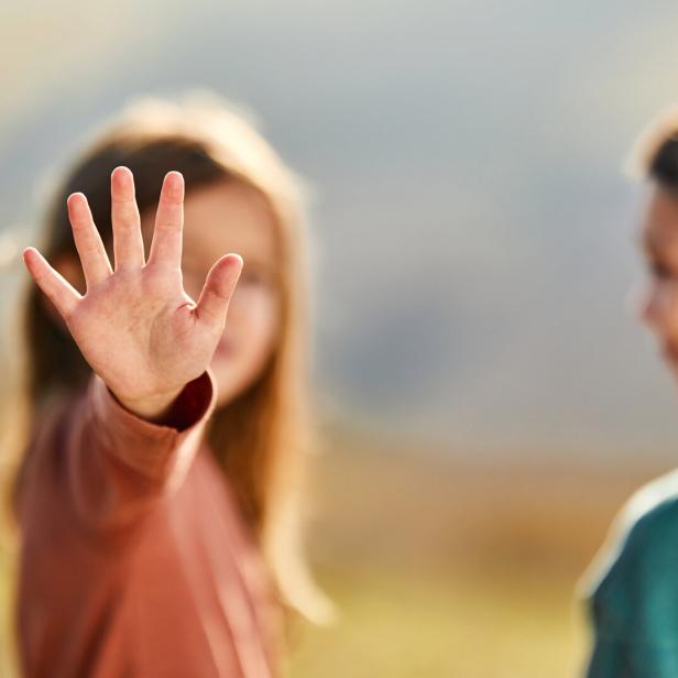 Ein Kind hält die offene Handfläche nach vorne, während ein weiteres Kind daneben steht.