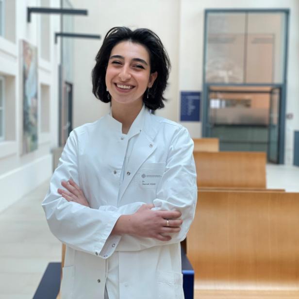 Hannah  Vizaei steht in einem langen hellen Gang der Wiener Zahnklinik.