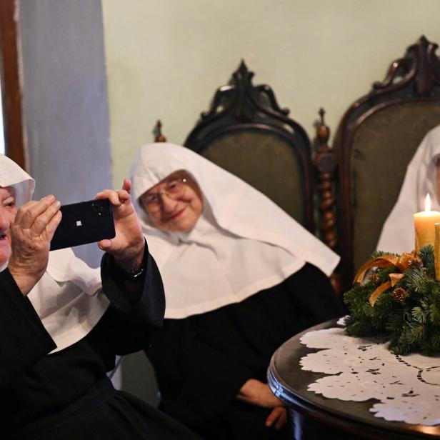 Drei Nonnen, eine hält ein Smartphone 