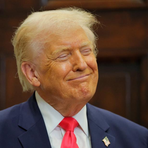 Donald Trump lächelt mit geschlossenen Augen in einem dunklen Anzug und roter Krawatte.