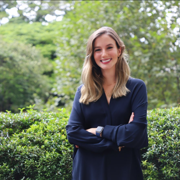 Luana Lopes Lara im Porträt-Format vor Garten.