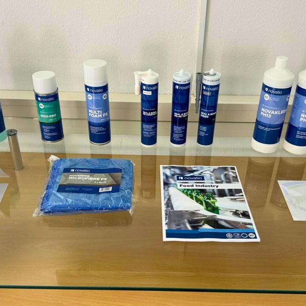 Verschiedene Novatio-Produkte und Infomaterialien auf einem Glastisch ausgestellt.