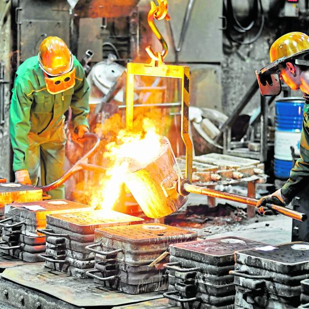 Group of workers in a foundry at the melting furnace - production of steel castings in an industrial company