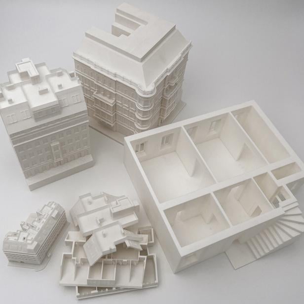 Mehrere detailreiche, weiße 3D-gedruckte Architekturmodelle auf weißem Untergrund.