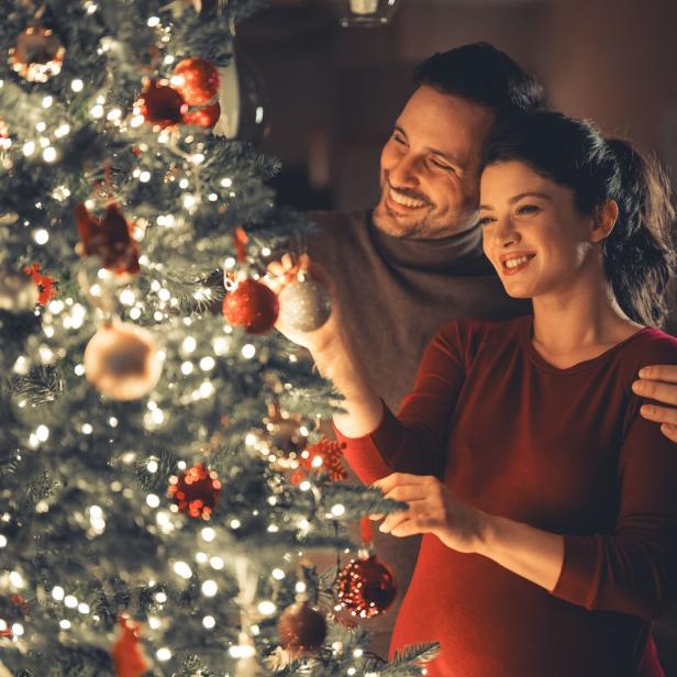 A loving happy young adult couple celebrating Christmas and decorating the Christmas tree
