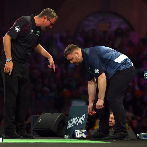 Ein Mann beugt sich mit blutender Hand nach unten, während ein Schiedsrichter auf den Boden zeigt.