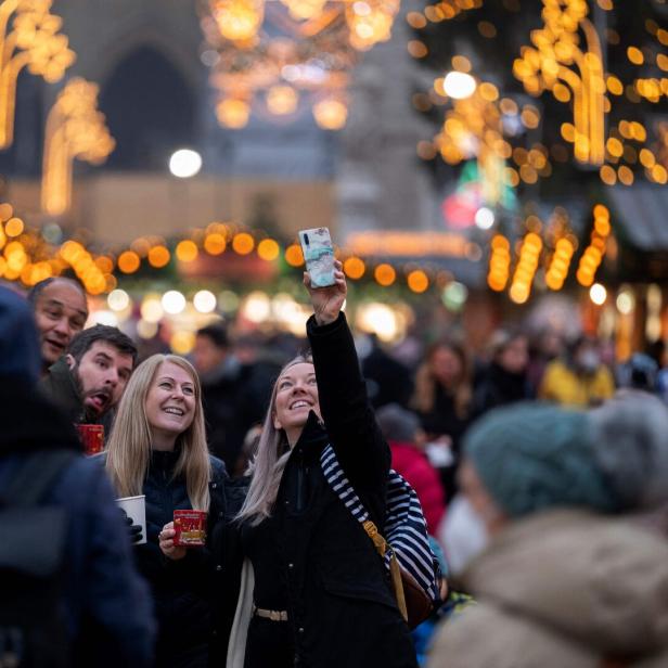 Auf einem Weihnachtsmarkt macht eine Frau ein Foto mit ihrem Handy.