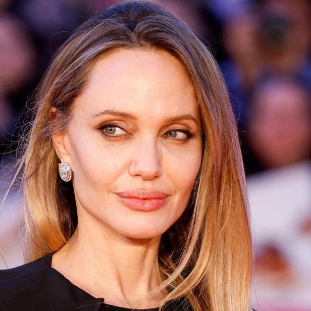 Angelina Jolie mit blondem Haar und Ohrringen blickt zur Seite.