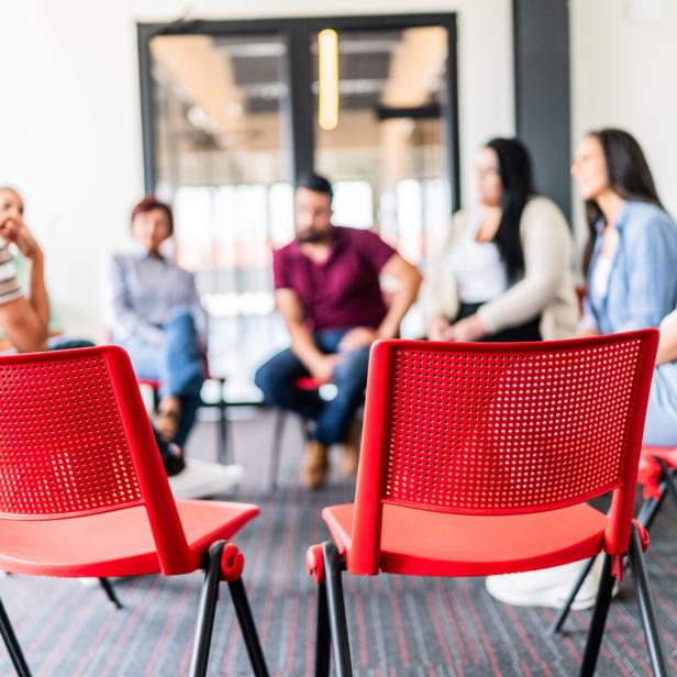 Eigentümerversammlung in einem Wohnhaus auf roten Stühlen