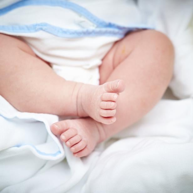 Babyfüße in einem Bett.
