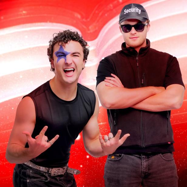 Ein Mann mit Stern im Gesicht posiert neben einem Security-Mann vor rotem Hintergrund.