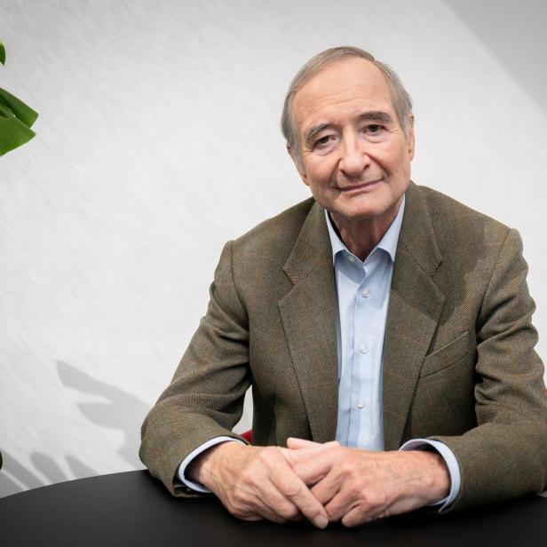 Christoph Leitl sitzt an einem runden Tisch und hat die Hände verschränkt.