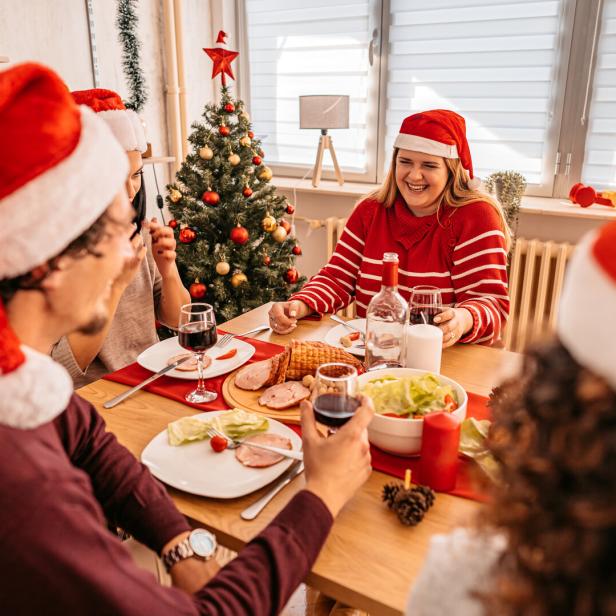 Menschen sitzen zusammen beim Tisch bei einem Weihnachtsessen.