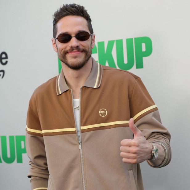 Pete Davidson mit Sonnenbrille und brauner Jacke zeigt den Daumen nach oben.